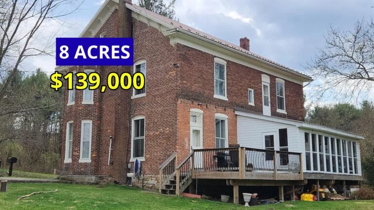 Exterior view of a stately brick farmhouse with turrets on 8 acres for sale at $139,900 in Huntingdon, Pennsylvania