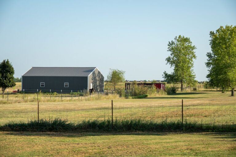 Dark metal building on open fenced acreage in rural Oklahoma