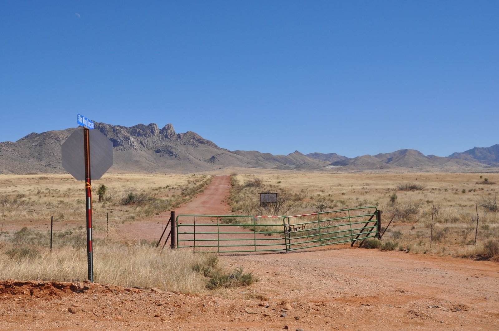 Ranch gate and dirt road on open grassland below the mountains near Valentine, West Texas