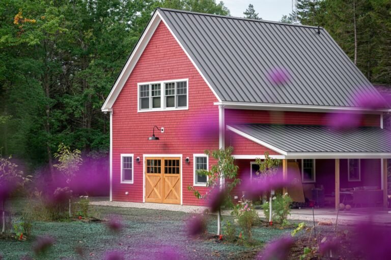 Barn-style home with a standing seam metal roof and covered porch in a rural setting