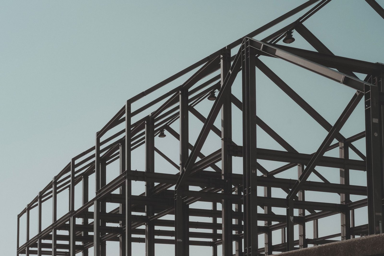 Structural steel frame and roof trusses of a building under construction against a clear sky