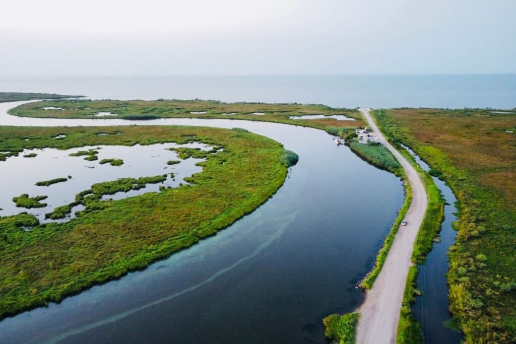 Aerial view of a bayou channel running beside a road through green wetland at sunrise near Lacombe, Louisiana