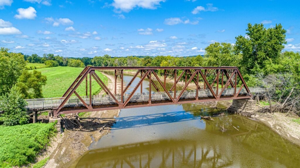 Old steel truss railroad bridge over a creek between green pastures in rural Missouri