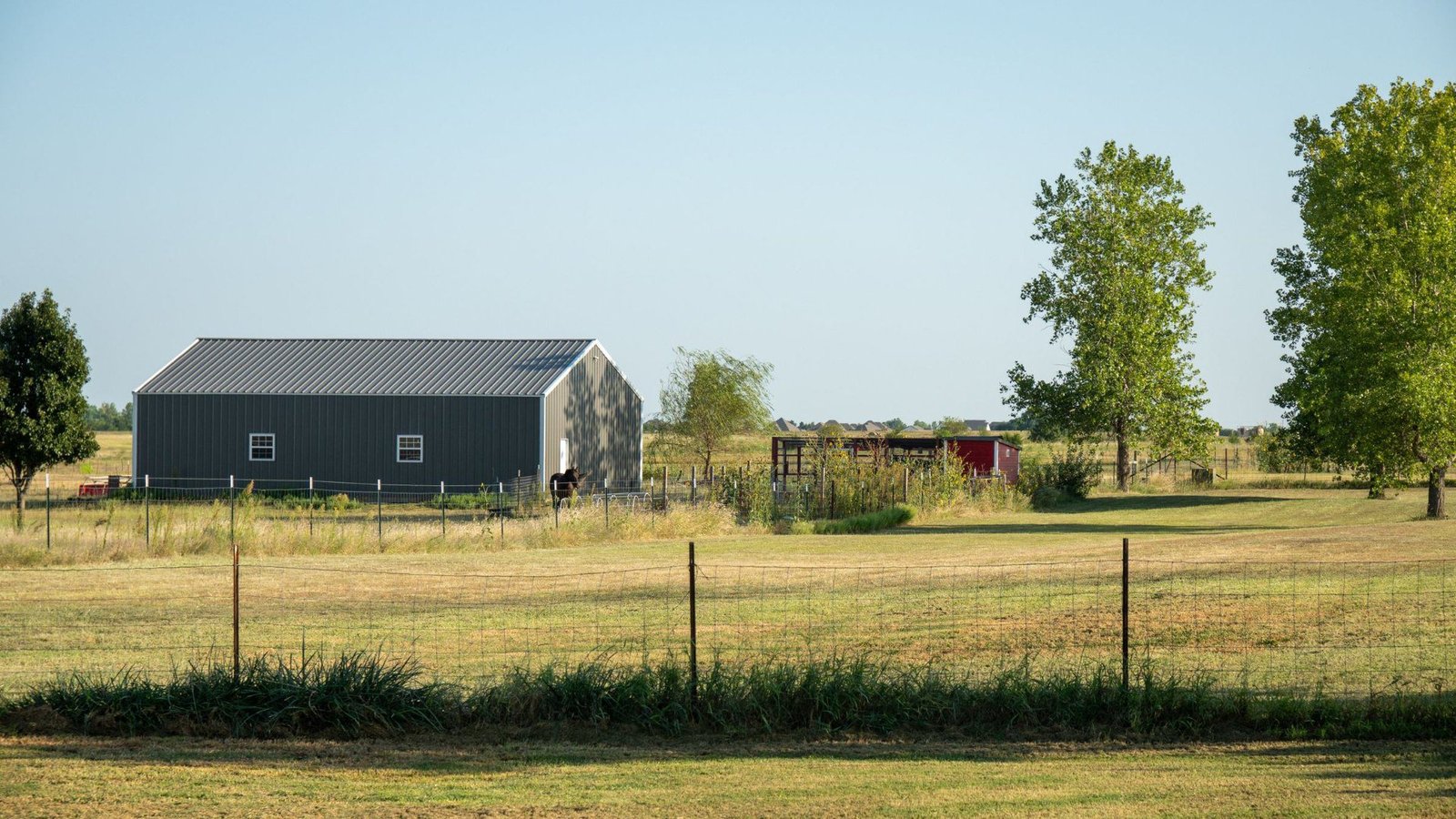Metal barn and fenced pasture on a farm in rural Oklahoma