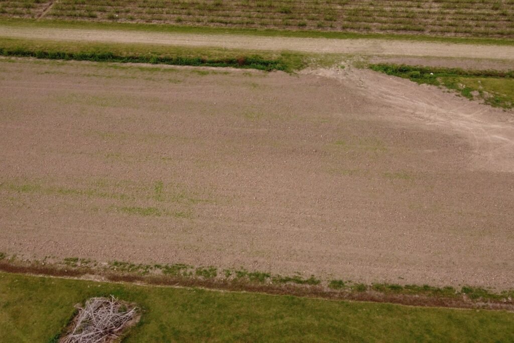 Low aerial view of a bare plowed field and a dirt farm track near Houma, Louisiana