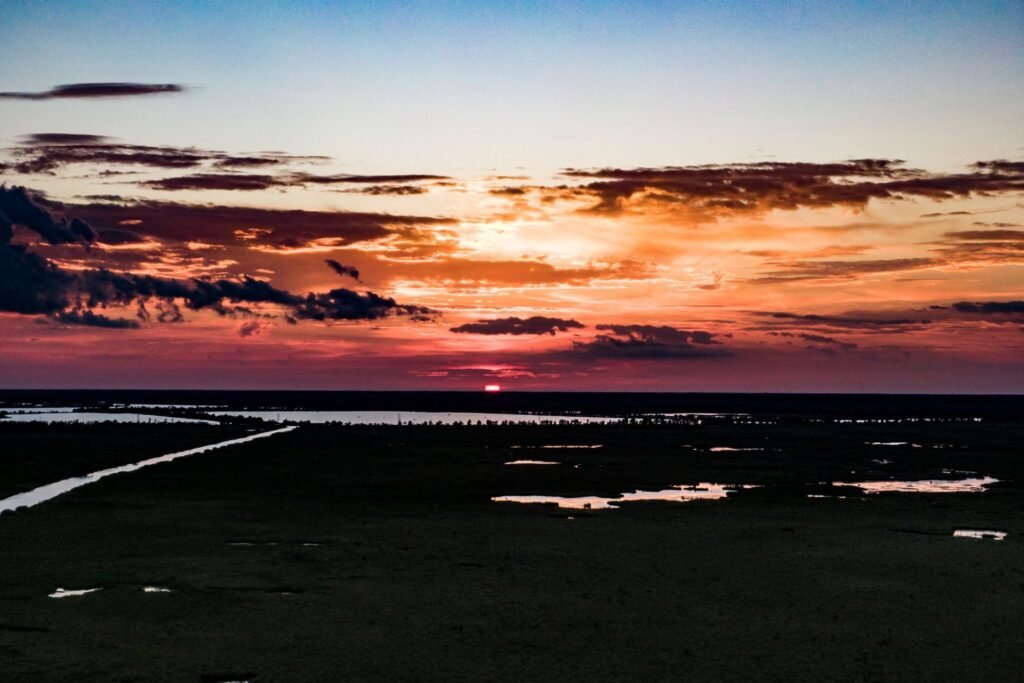Aerial view of an orange and red sunset over dark marshland near Madisonville, Louisiana