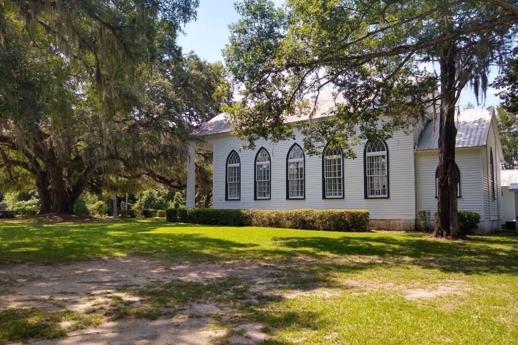 White wooden church under big oak trees with a green lawn in Garnett, South Carolina